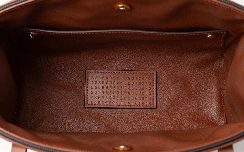 Top-down view of a Gucci interior authentication tag showing the embossed serial number with digits-only format used to verify a genuine Gucci bag