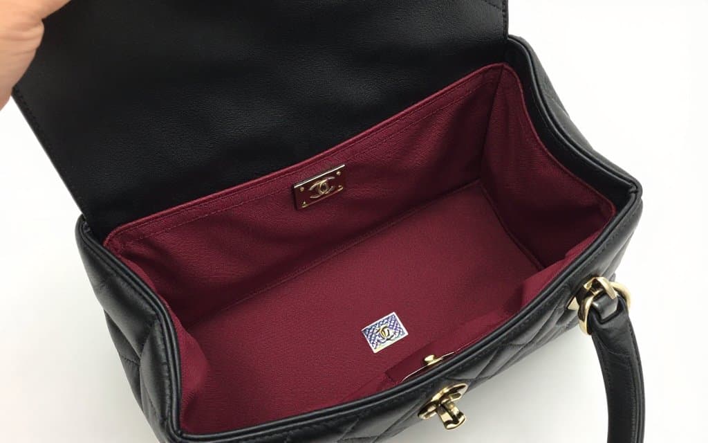 Interior of an authentic Chanel bag showing the hologram sticker and burgundy grosgrain lining that help authenticate Chanel bags at thrift stores