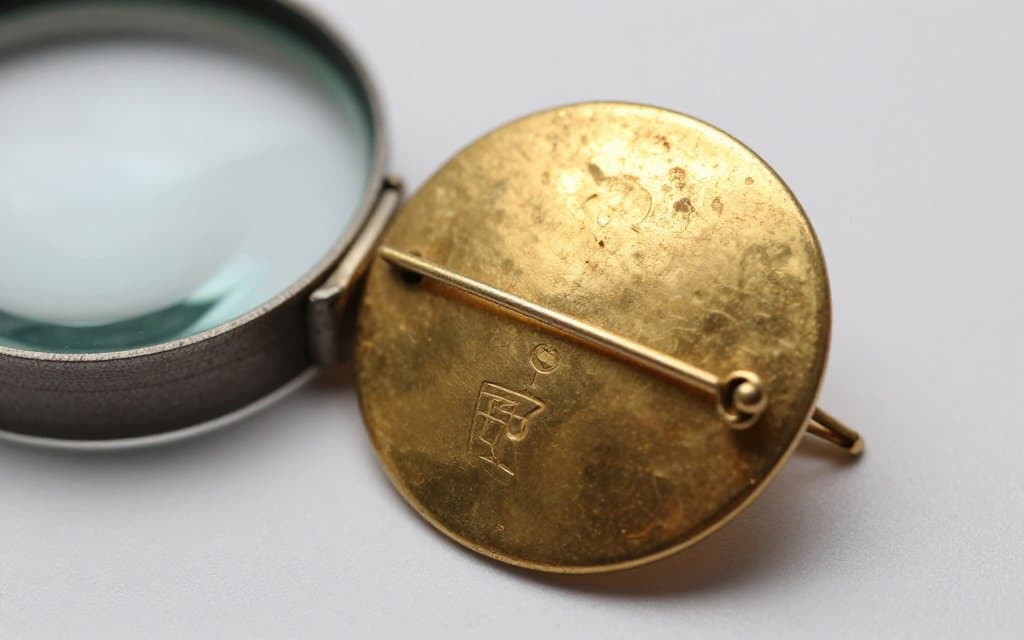 Macro view of a maker's mark on the back of an antique costume jewelry brooch.