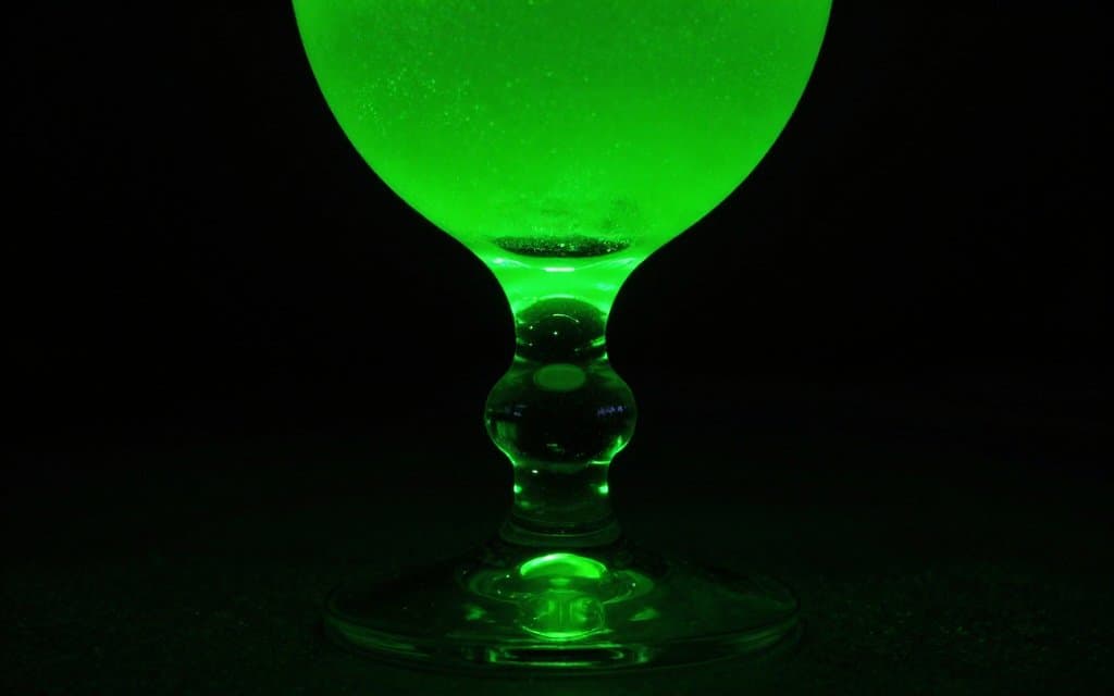 Green glass goblet glowing neon green under a 365nm UV black light