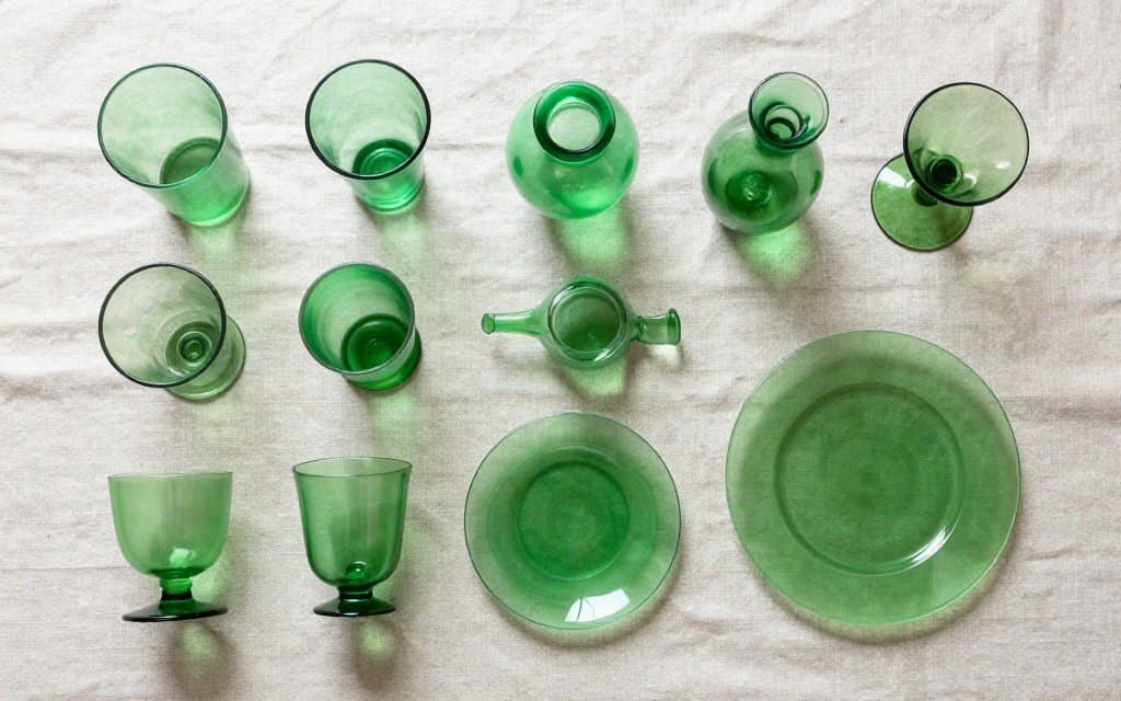 Top-down view of glowing glass forms, cups vase plate and compote