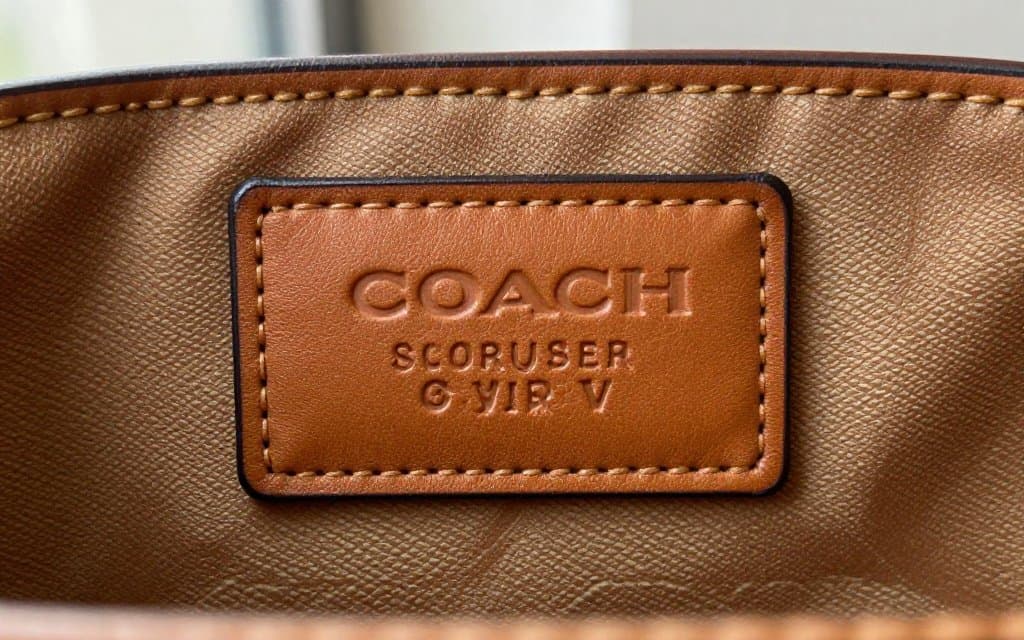 Macro of a coach bag serial number embossed on the interior leather creed patch of a vintage tan bag