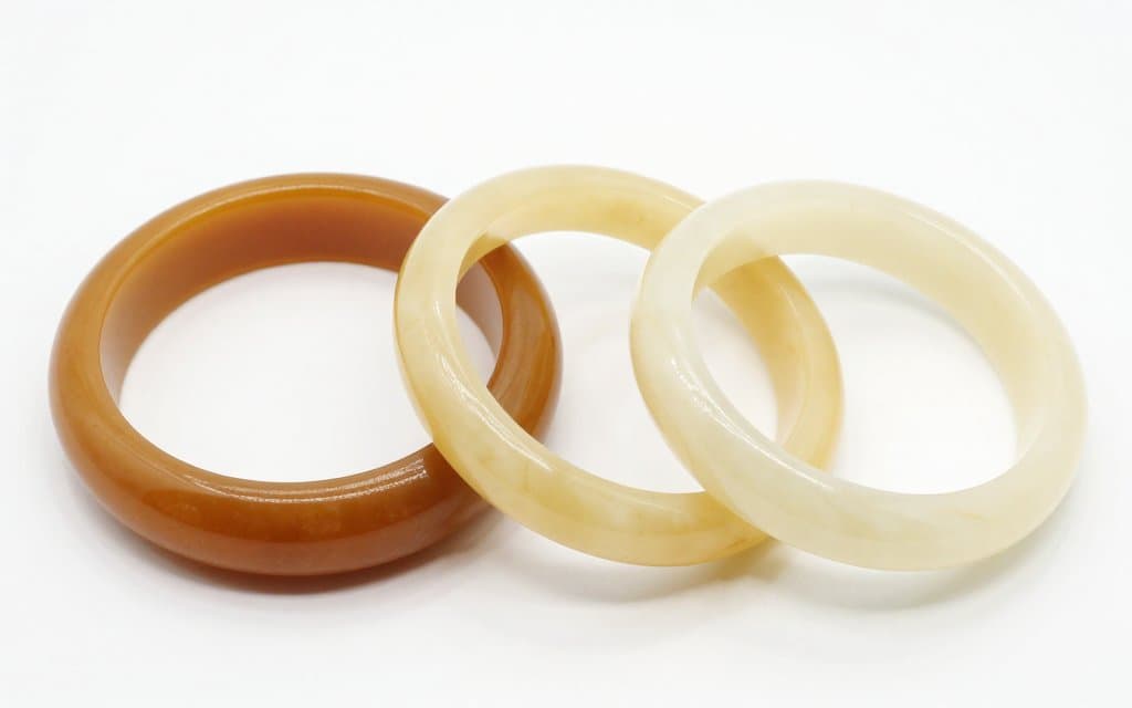 Comparison of a bakelite bangle beside lighter lucite bangles to tell them apart.