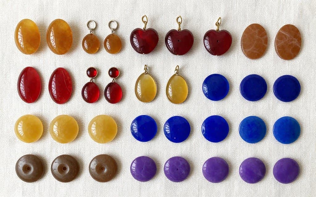 Flat lay of vintage bakelite jewelry sorted by color from butterscotch to rare cobalt blue.