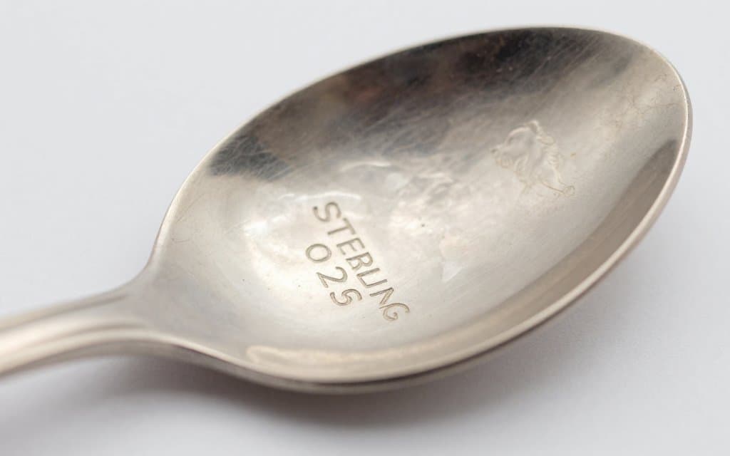 Macro close up of sterling silver marks stamped on the back of a spoon handle reading sterling and 925
