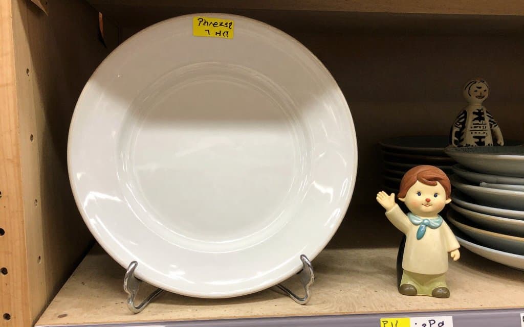 Vintage Hummel plate and figurine on a thrift store shelf with price stickers