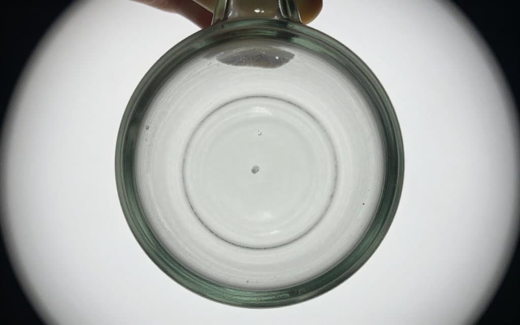 Top down view of a pontil scar on an antique bottle base used to date the glass