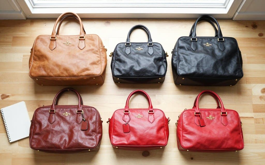 Top down flat lay of vintage Coach purses with resale price tags