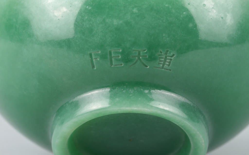 Macro of a Fire King jadeite backstamp molded into a green glass base