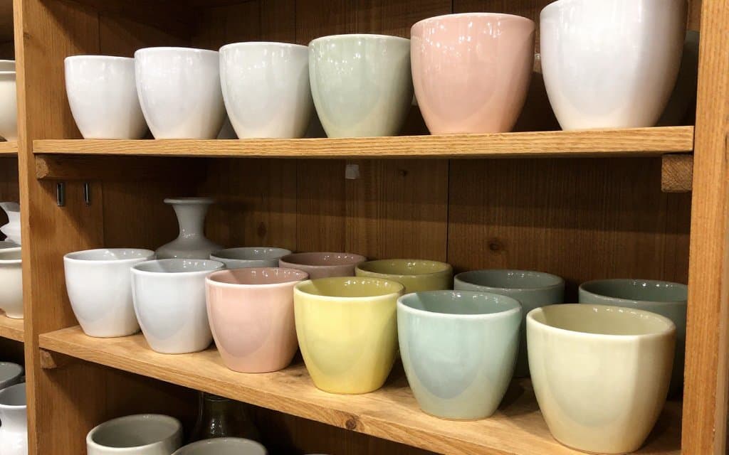 Shelf of pastel McCoy pottery planters and vases in white, pink and green glazes
