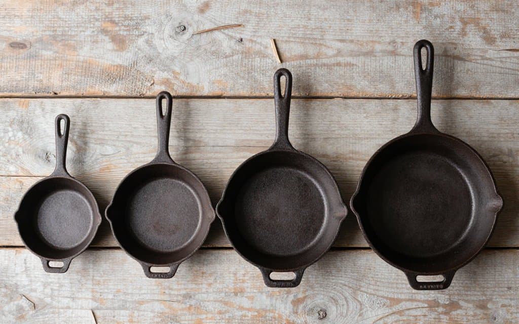 Five vintage cast iron skillet sizes lined up from small to large