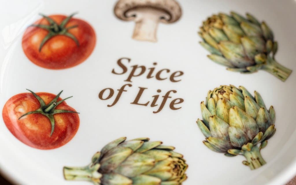 Macro of the Pyrex Spice of Life pattern vegetables and French text on a white CorningWare casserole with a clear glass lid