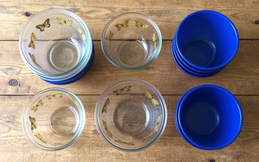 Top down view of common vintage Pyrex bowls in butterfly gold and blue stacked on a wood table