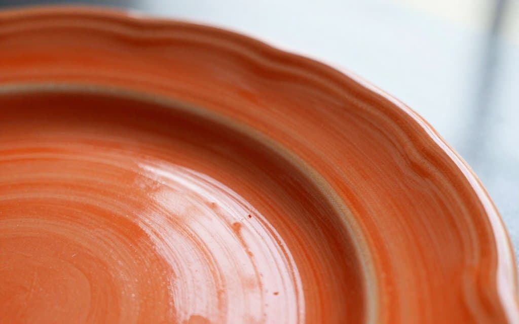 Macro view of the orange-red glaze on a radioactive Fiestaware dinner plate showing its concentric rings