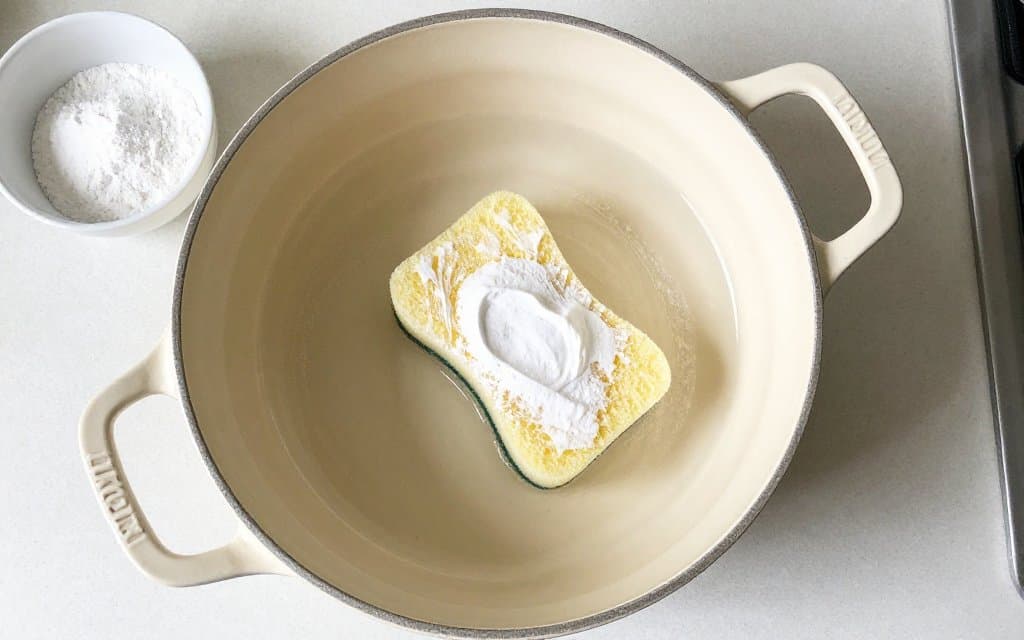 Top-down view of baking soda paste lifting stains inside an enameled pot, showing how to clean Le Creuset