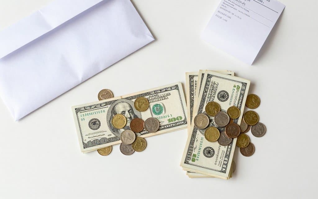 Cash split into two piles beside a shipping envelope, illustrating how eBay fees apply to shipping and tax